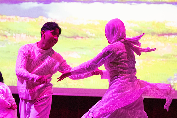 Dance performance under pink stage lighting